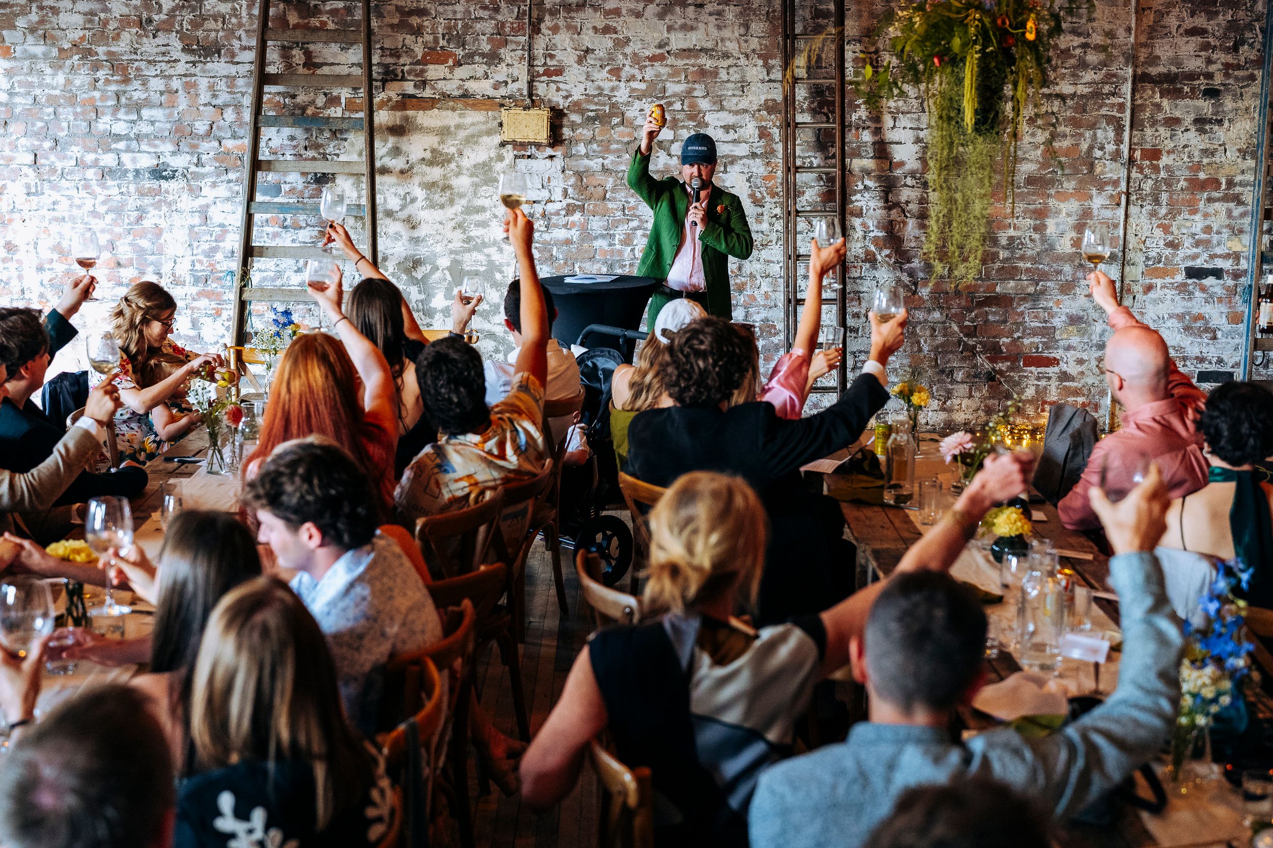 Wedding MC energizes crowd as guests raise hands at a lively indoor reception celebration in Liverpool.