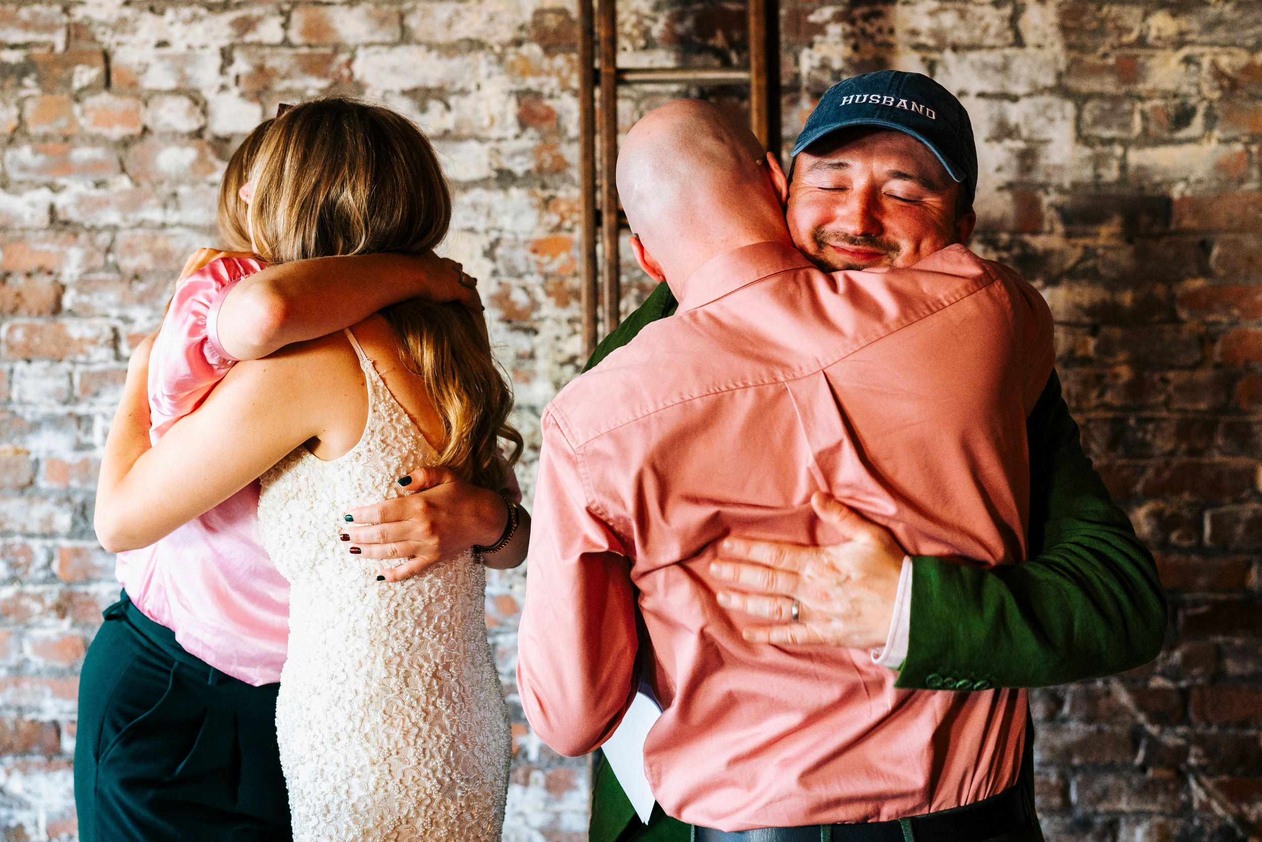Emotional wedding moment as bride and groom share heartfelt hugs with tearful guests at reception.