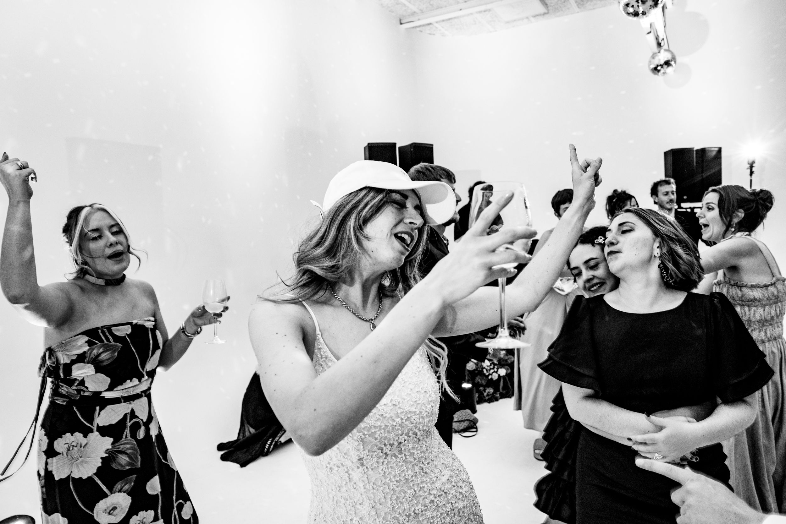 Bride and guests dancing exuberantly on the white dance floor at a wedding reception.