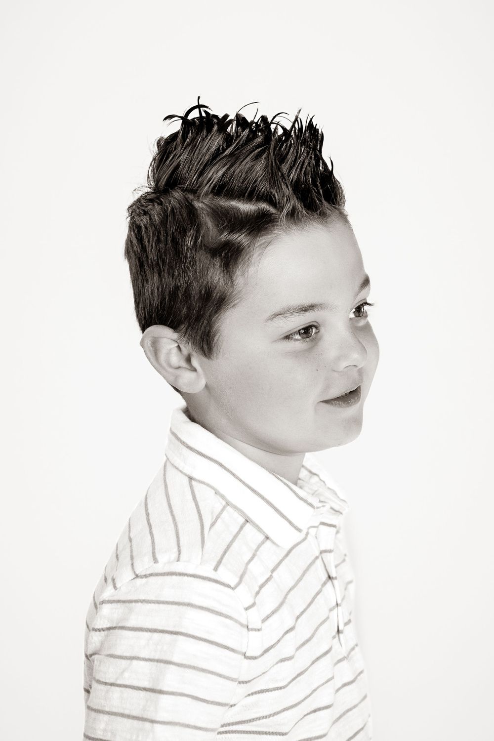 Black and white portrait of a young boy with spiked hair wearing a striped polo shirt, smiling slightly.