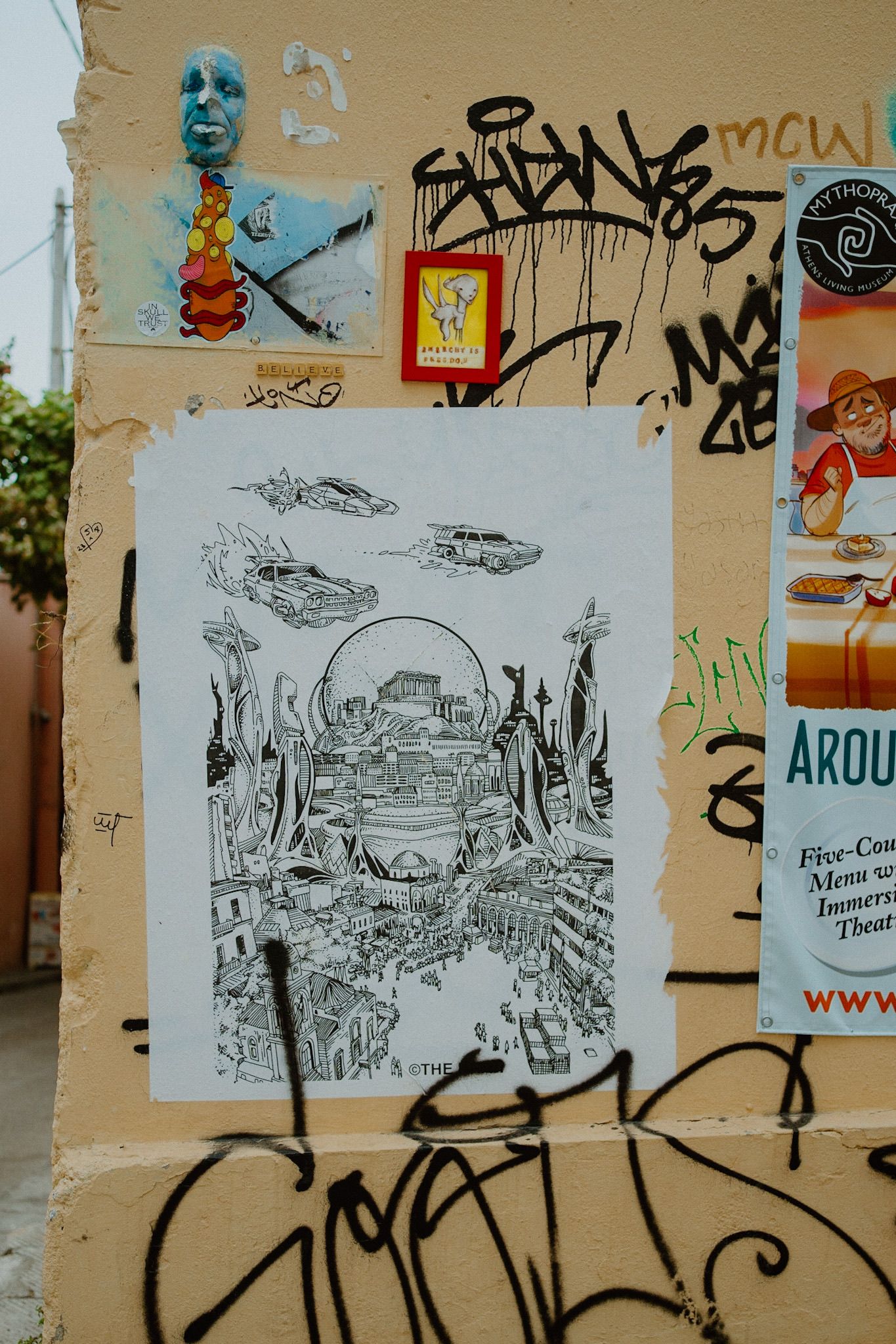 Street art wall featuring a black and white sketch of an underwater or fantasy landscape among graffiti and posters.