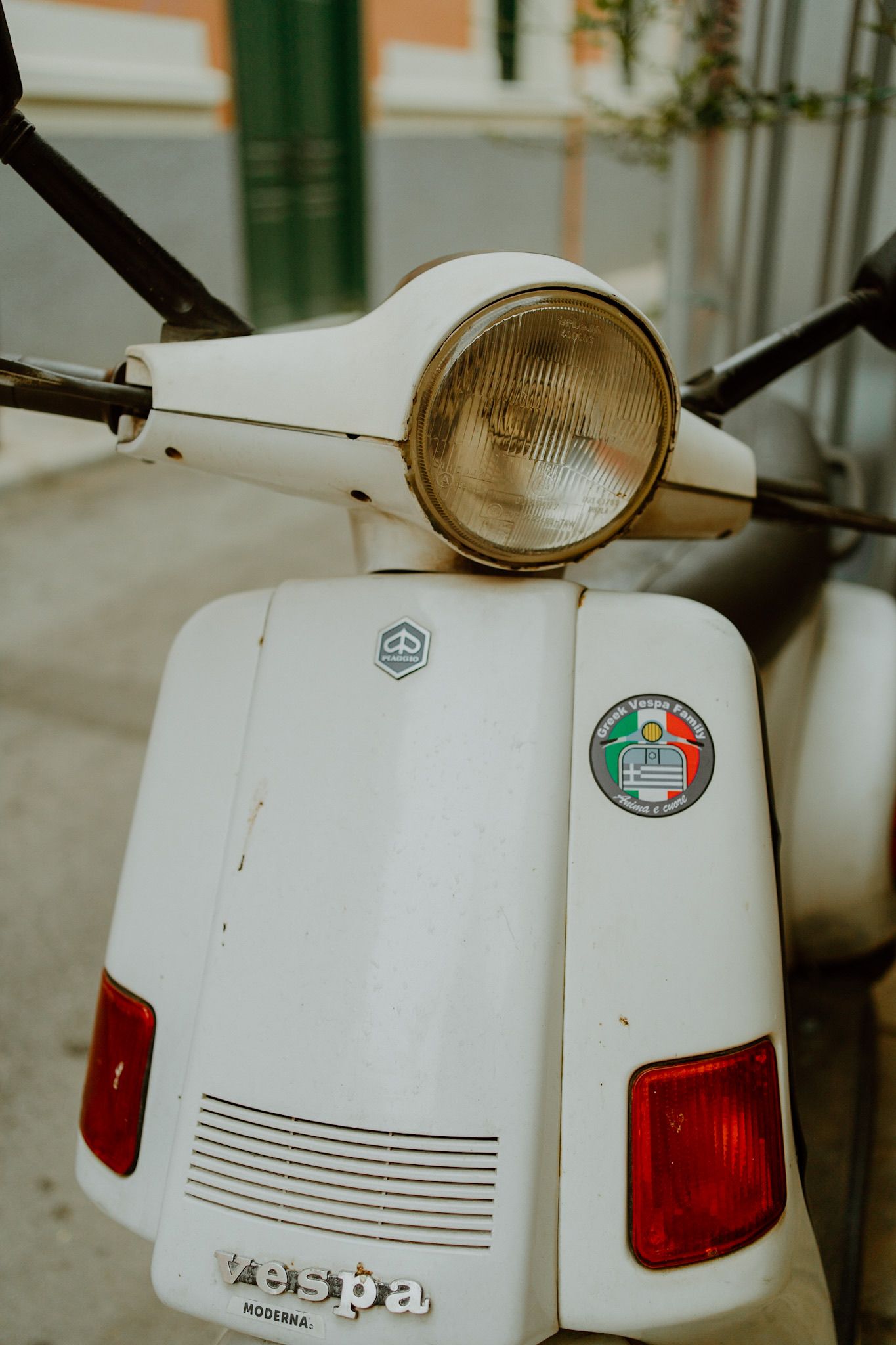Vintage white Vespa scooter headlight detail with retro Italian styling and decorative stickers.