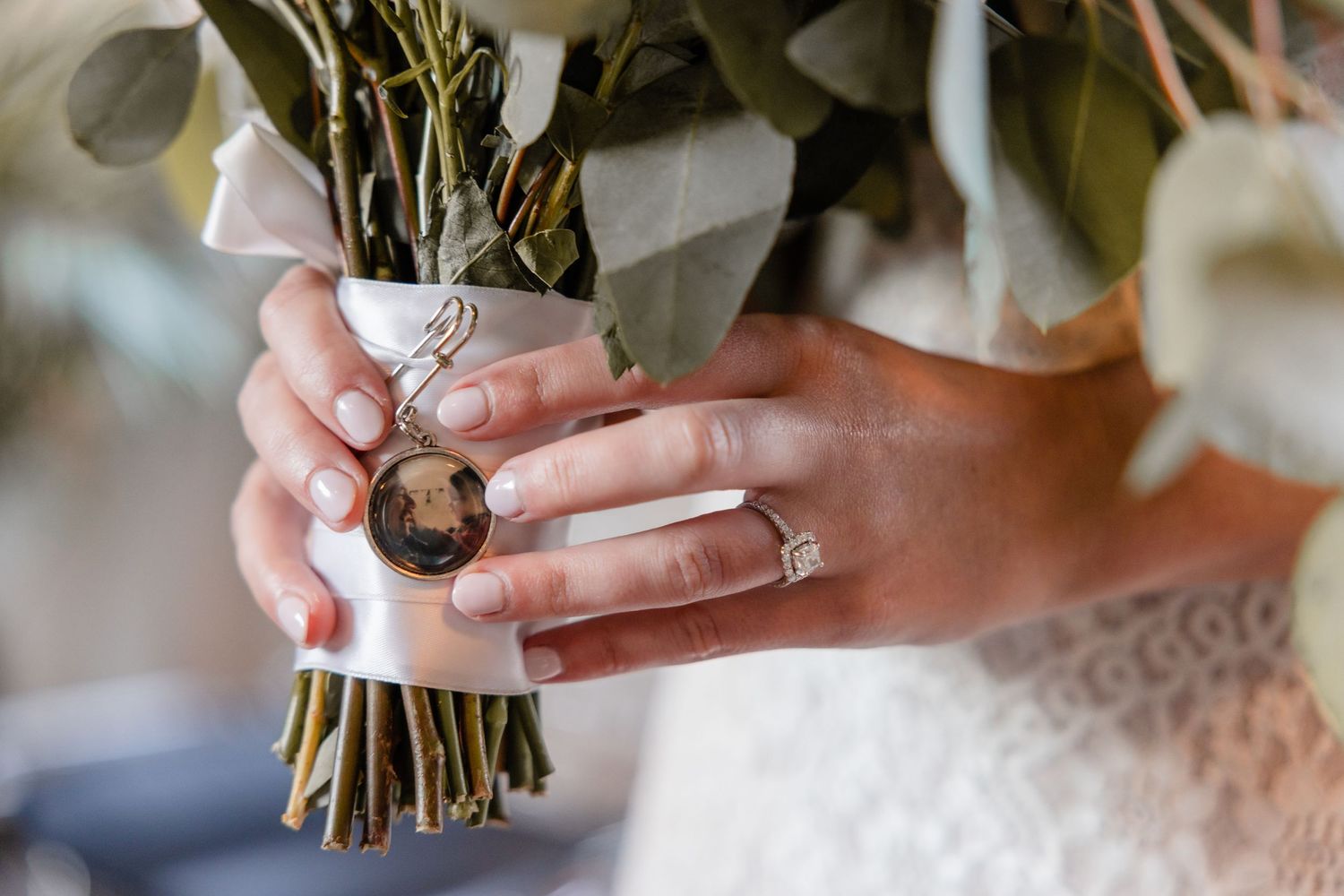 A person holds a bouquet of white flowers wrapped in brown paper against a blurred background.