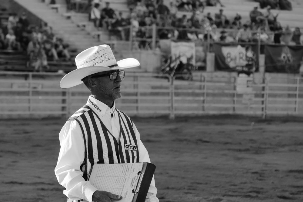 Official in traditional striped uniform and cowboy hat at rodeo.