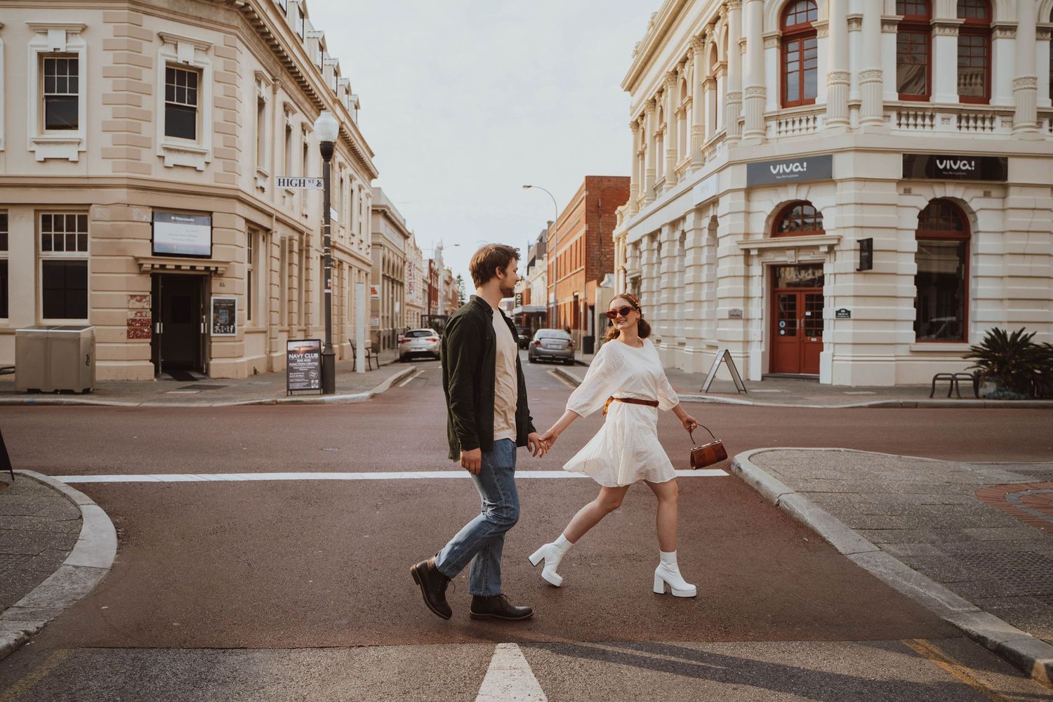 Couple dancing on a historic city street corner with vintage architecture and warm sunset lighting.