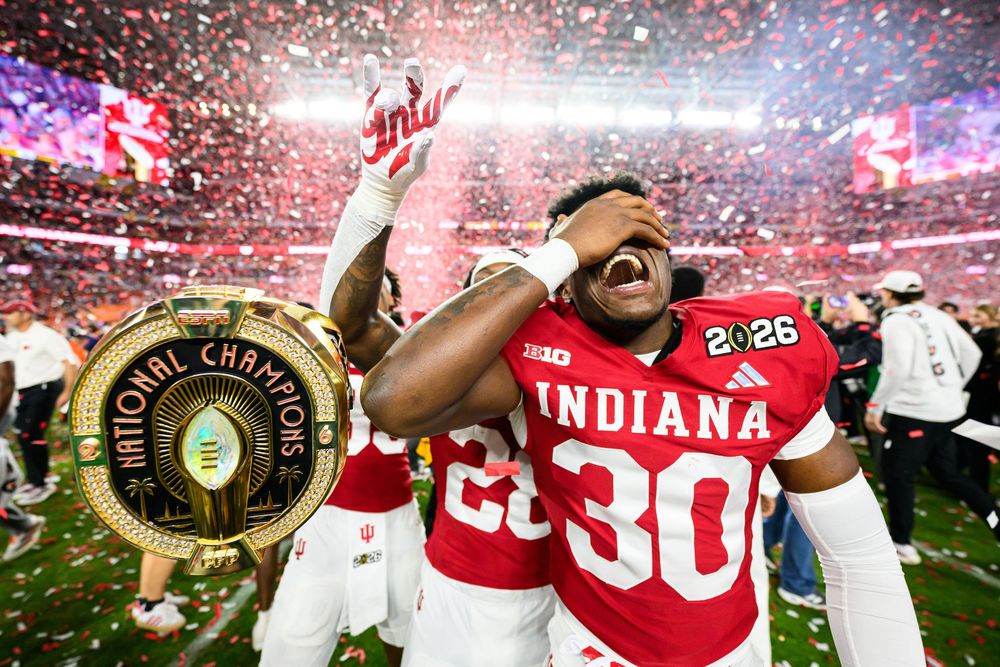 Football players celebrate with confetti falling during a championship game victory celebration at a packed stadium.