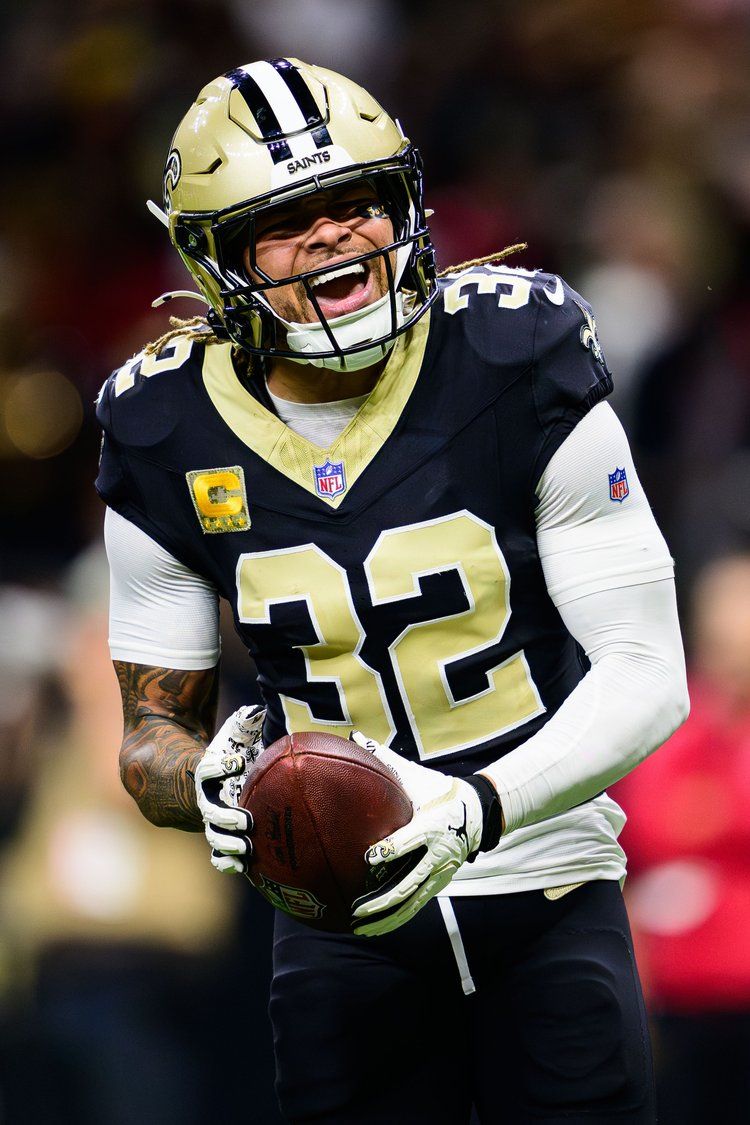 New Orleans Saints player in black and gold uniform celebrating with football during NFL game.