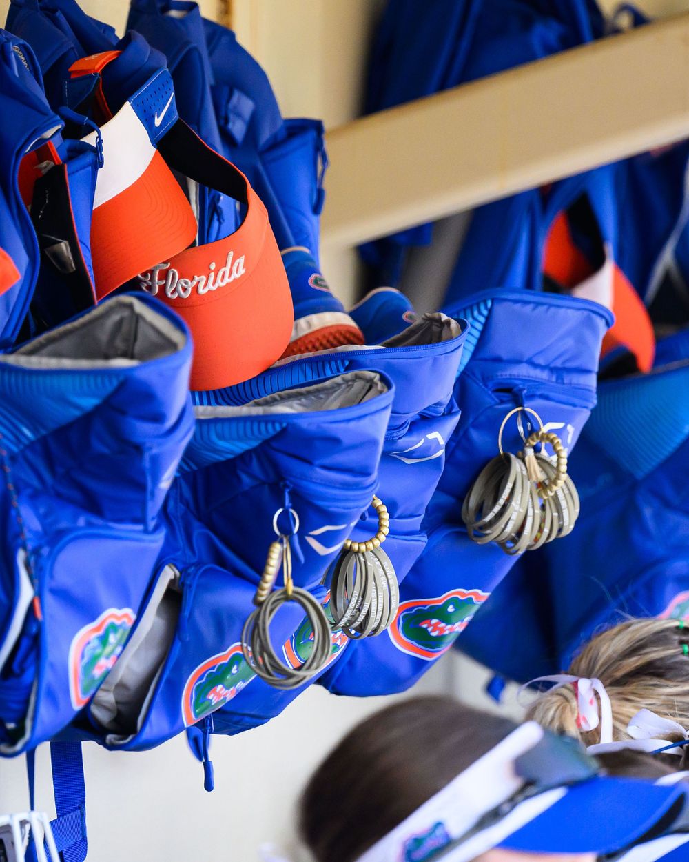 Florida Gators baseball team equipment with blue bags and keychains arranged in dugout storage area.