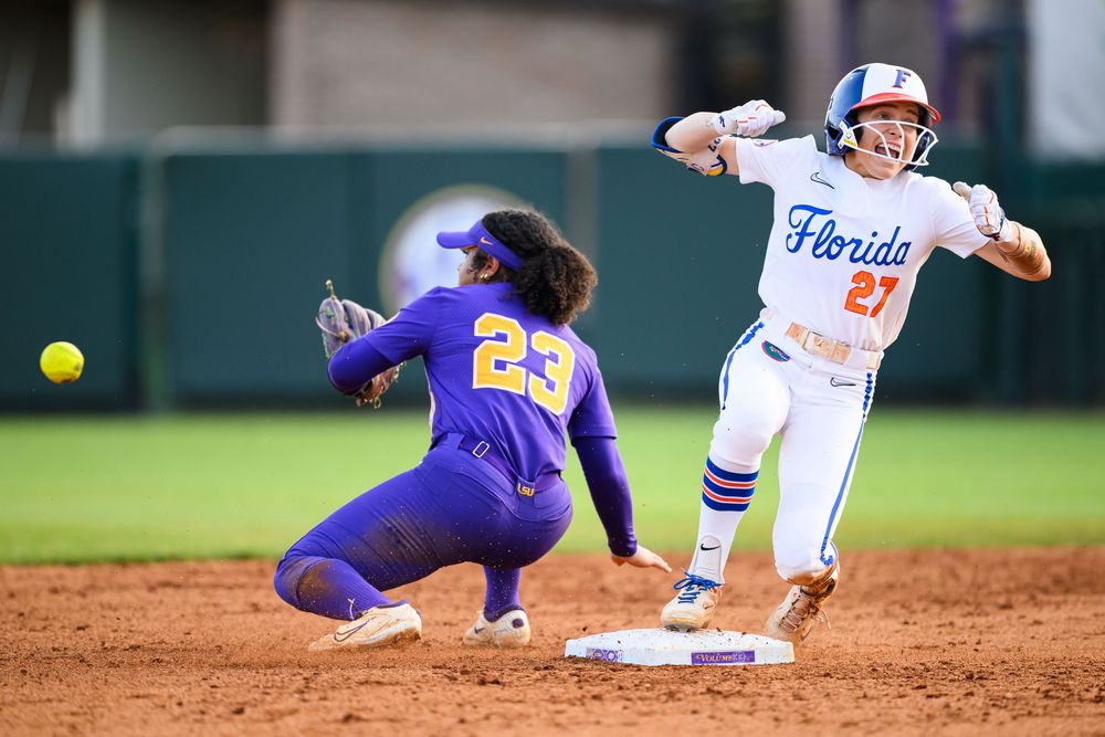 Two softball players in action during a game as one slides into second base while the other attempts to make the play at the base.