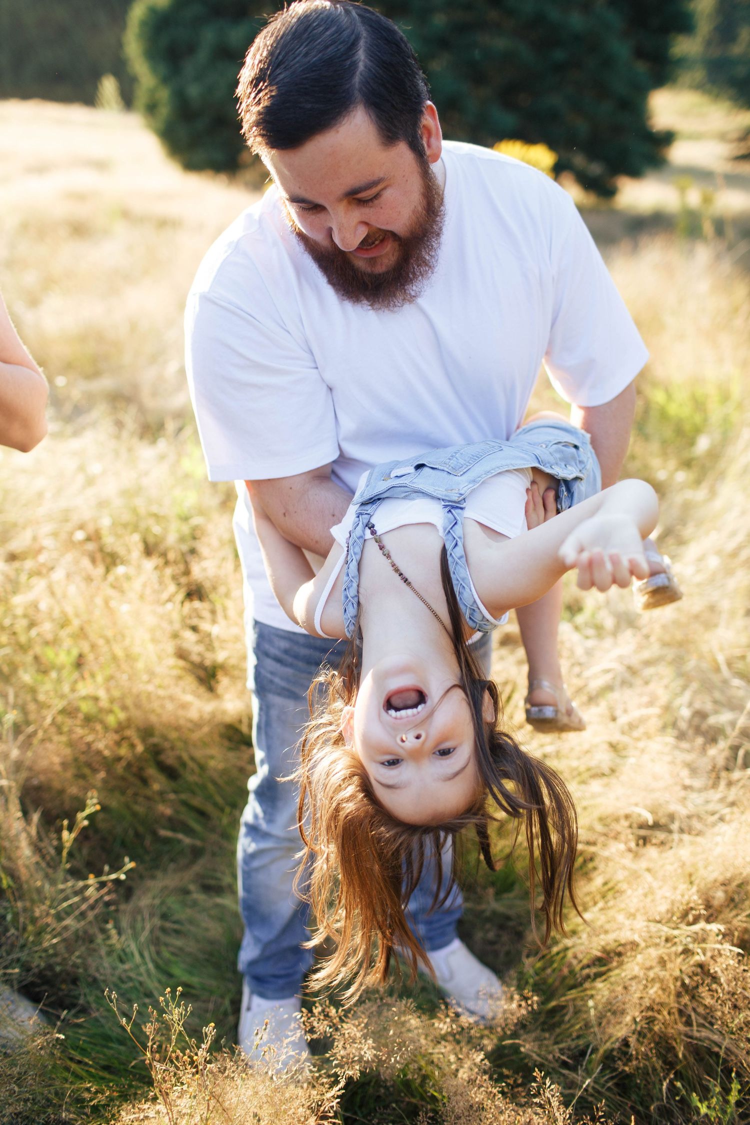 Everett Family Photographer: A father carries his young daughter during a fun family photo session at Wayne Park Golf Course in Bothell WA