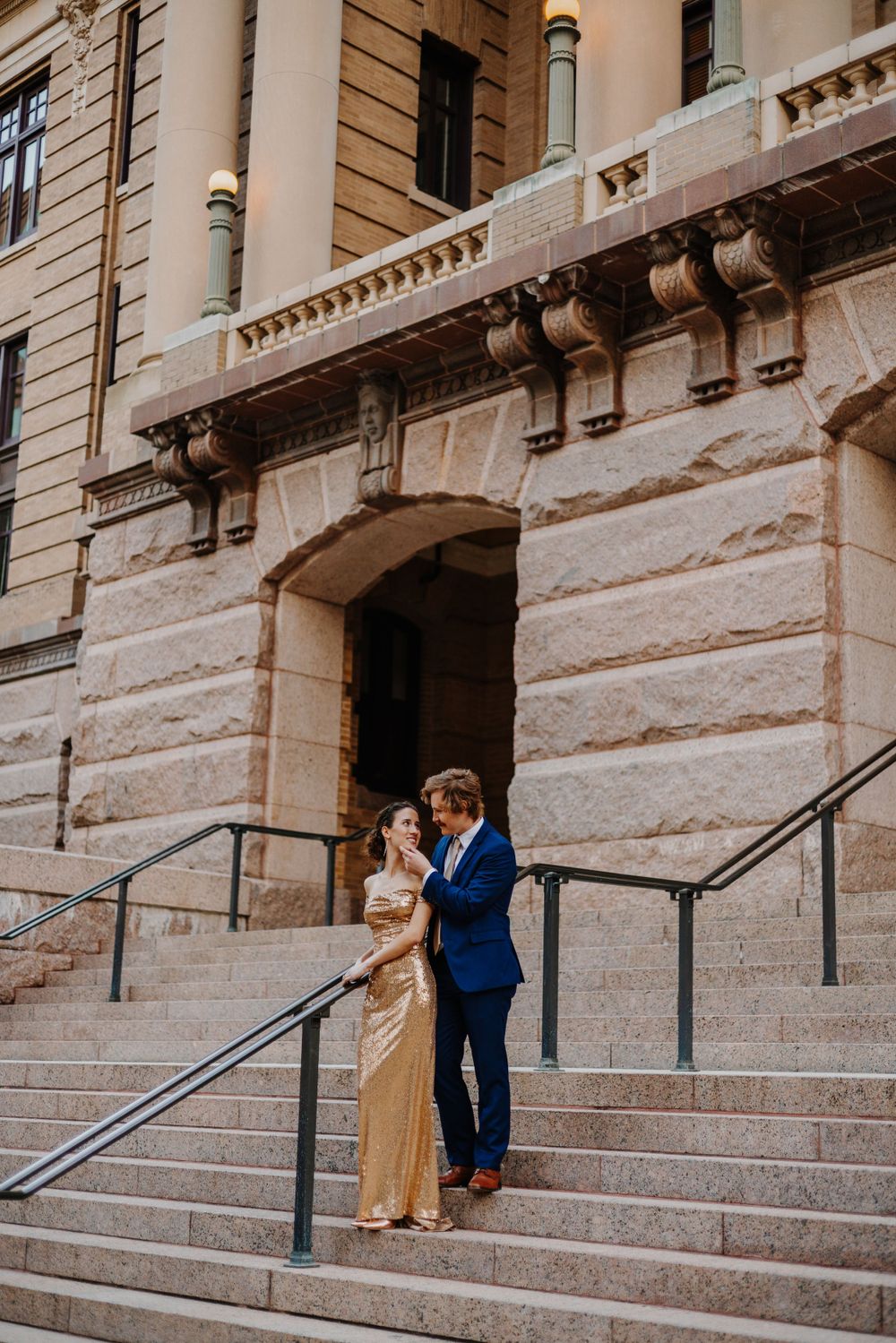 Romantic couple shares intimate moments on historic stone building steps during engagement photo session.