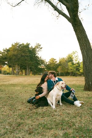 A couple and their dogs enjoy a casual moment together on a hillside.