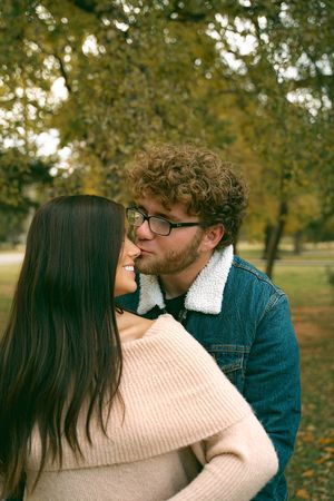 Intimate autumn photoshoot of couple with ultrasound photos in park.