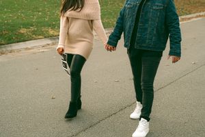 A couple walks together on a path during autumn holding ultrasound photos.