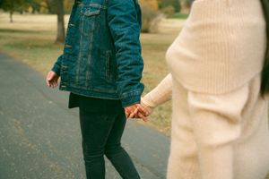 Two people walking together on a path during fall season.