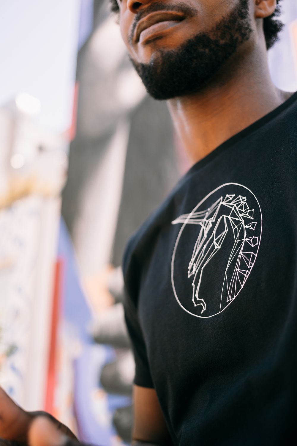 Close-up of person wearing black t-shirt with minimalist circular white line art design showing a dancing figure.