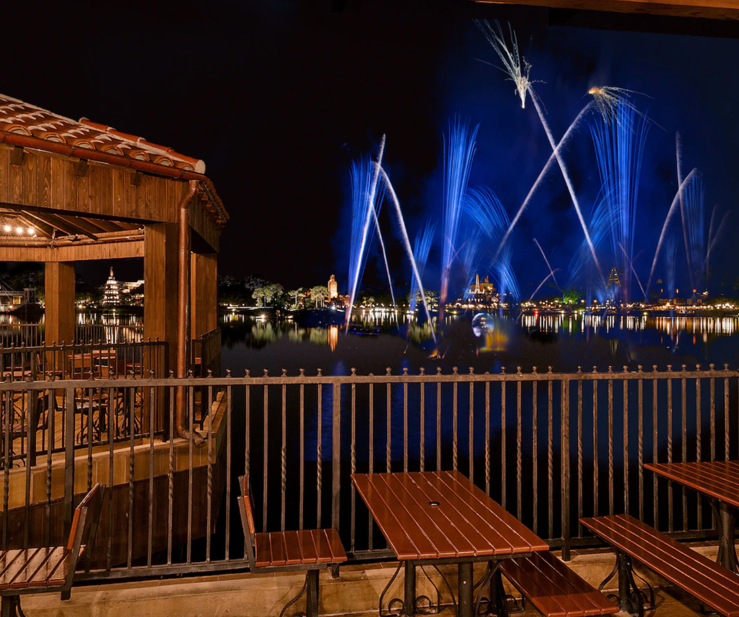 Nighttime view of illuminated blue light show over waterfront dining patio.
