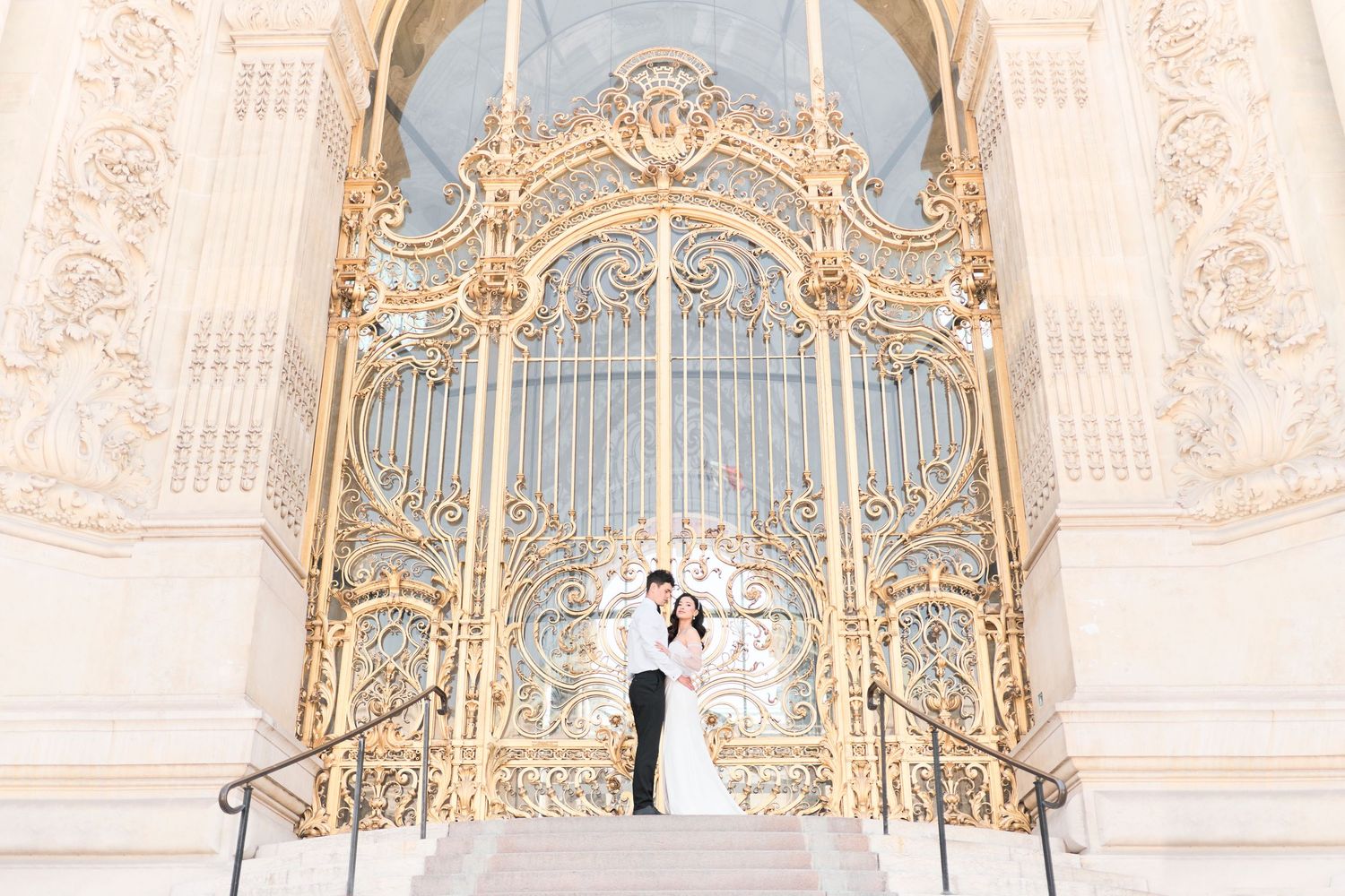 Paris wedding photographer captures a romantic photo of a bride and groom outside the stunning Petit Palais golden gates in Paris, France