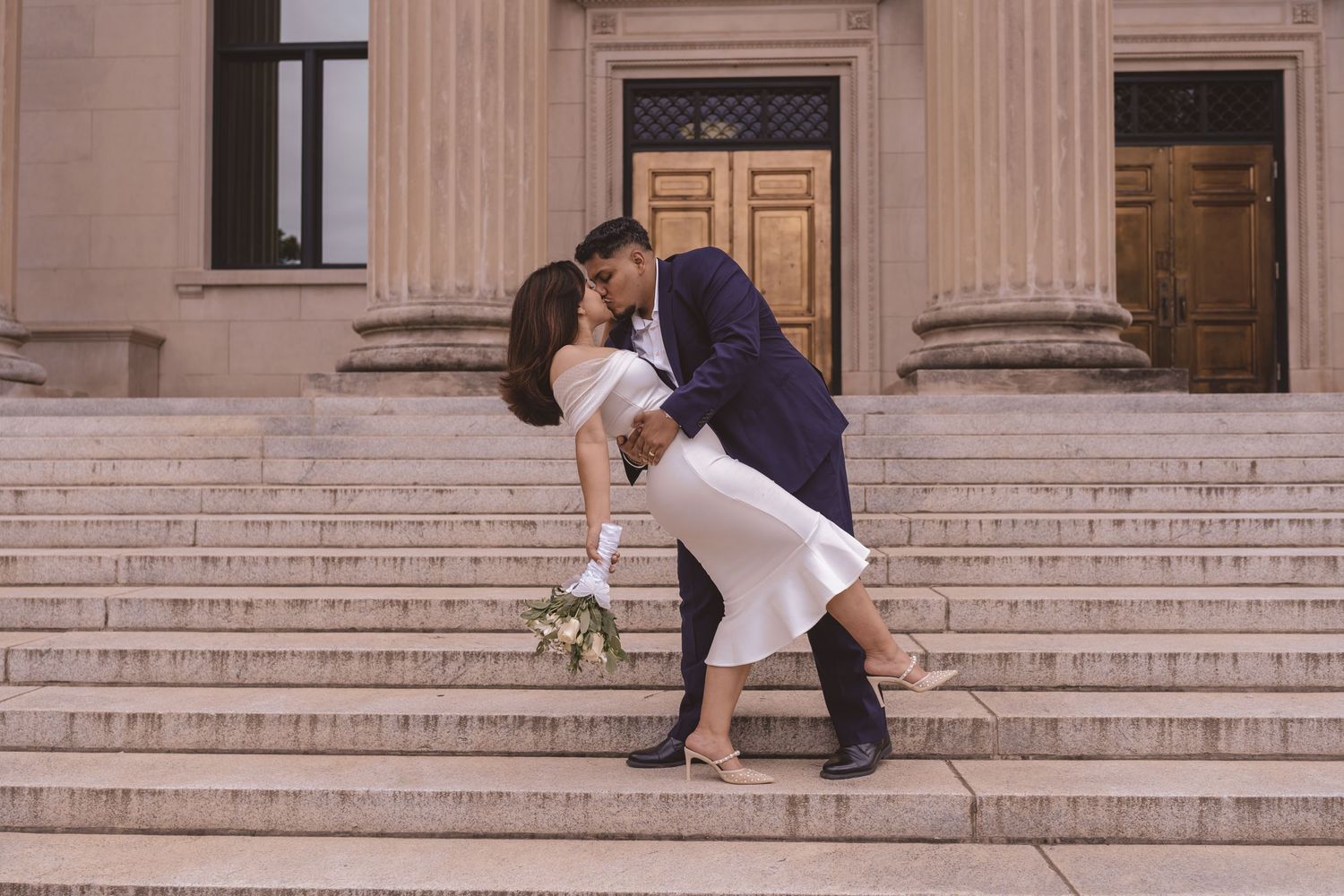 Bride and groom kissing outside Mecklenburg County Courthouse in Charlotte, NC