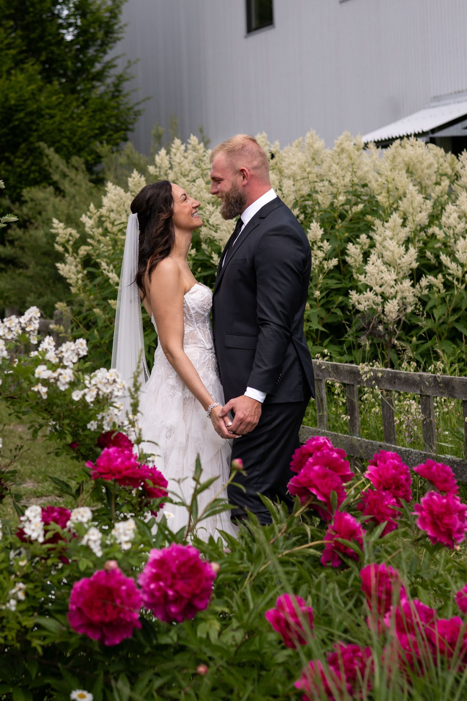 Romantic garden wedding scene with vibrant pink peonies in foreground.