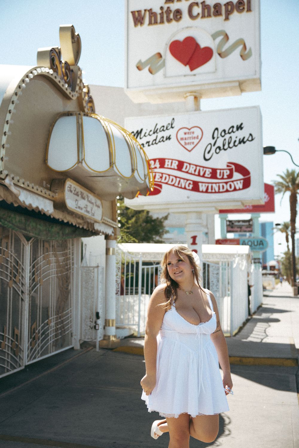 A sunny photo showing someone in white dress outside Little White Chapel's drive-up wedding window.