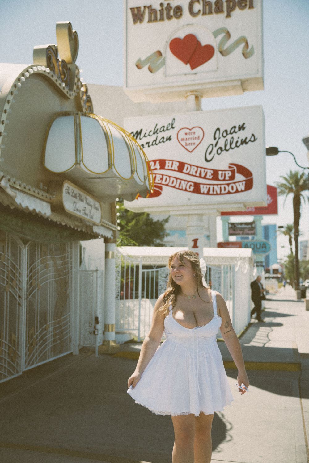 Vintage-style photo showing a person in white dress by the Little White Chapel's retro signage.