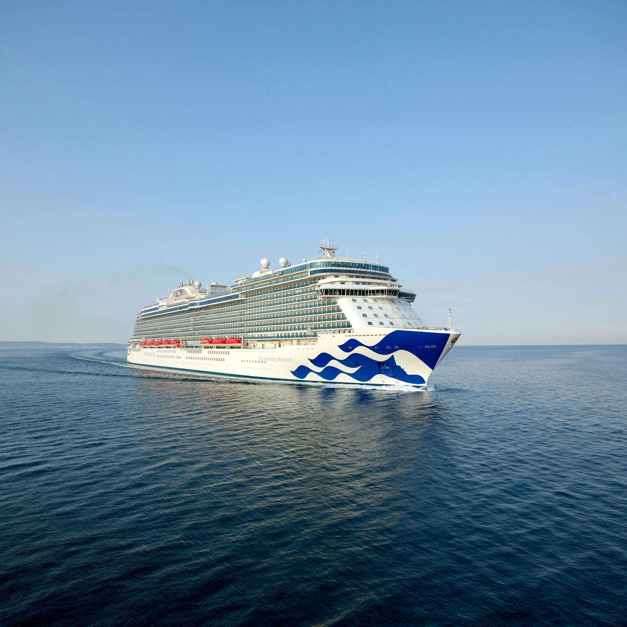 Luxury cruise ship with distinctive blue and white hull design sailing across calm ocean waters at sunset.