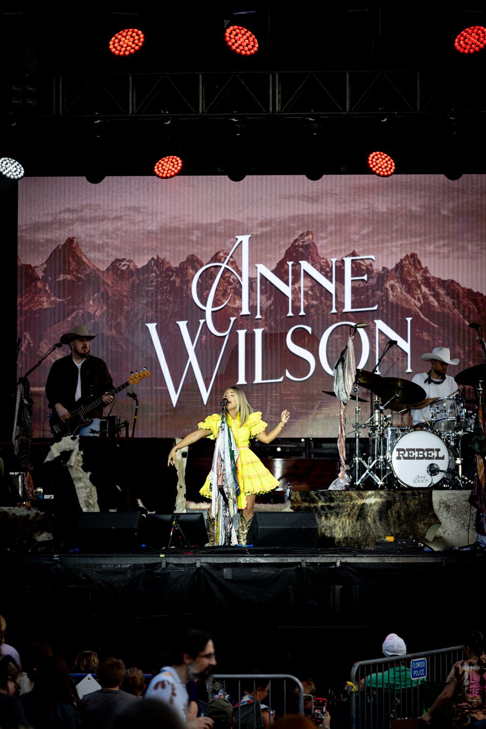 Wide concert stage view with red lighting and text display on mountain backdrop.
