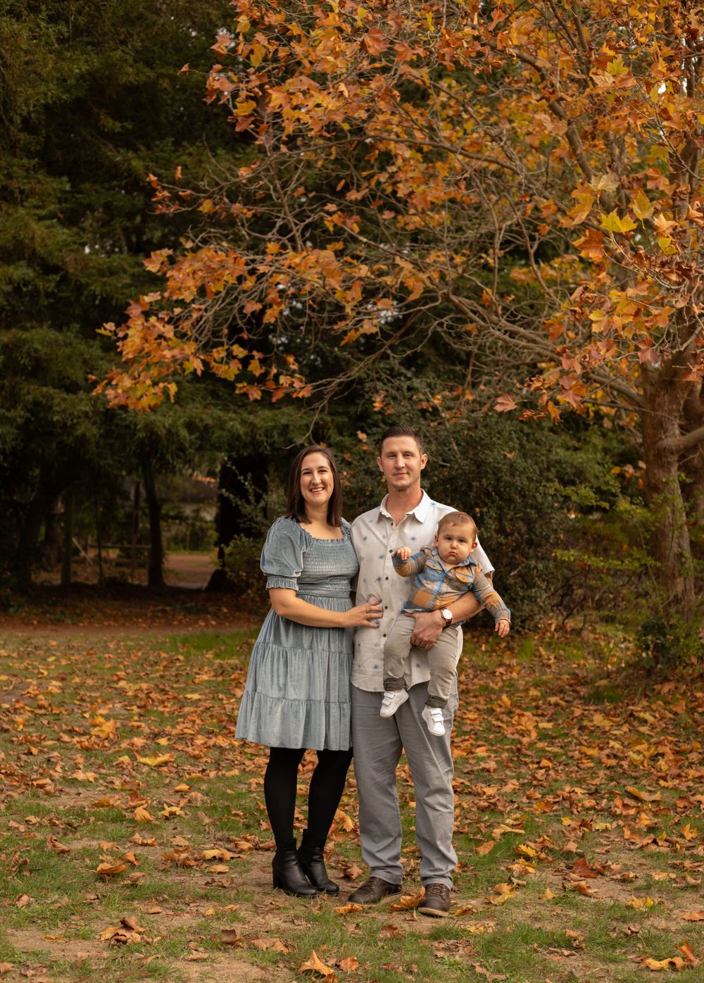 Natural family photos taken outdoors with beautiful fall foliage and scattered leaves.