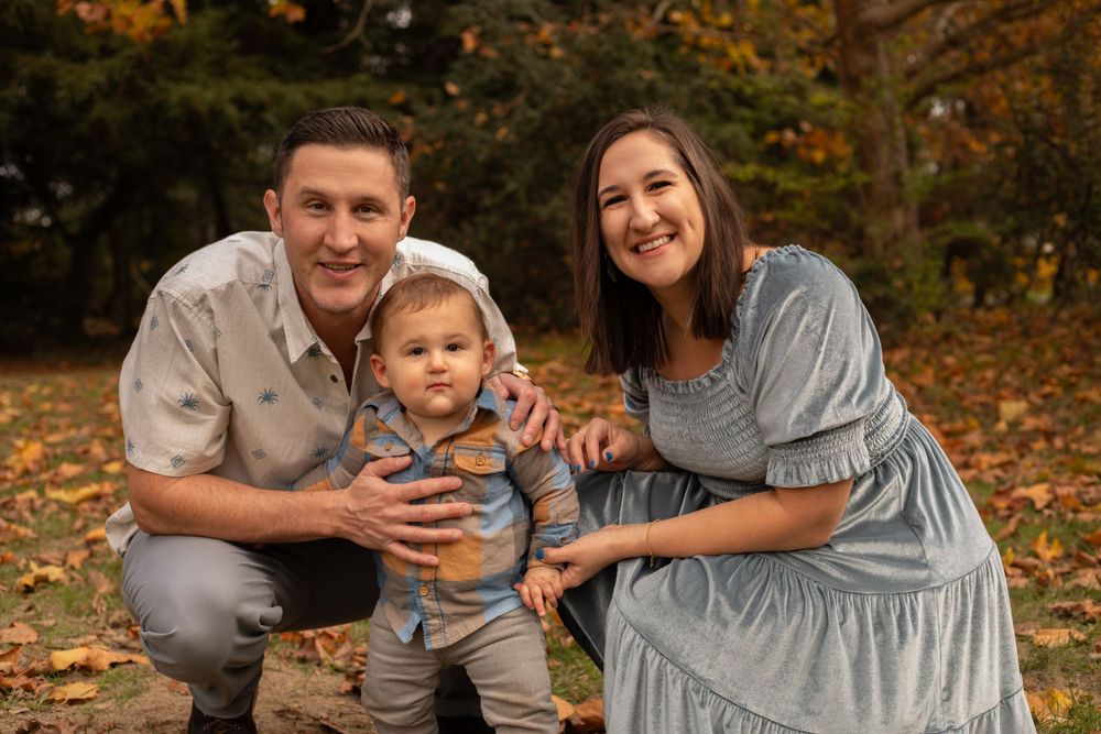 Intimate family portrait session during fall with warm autumn colors in the background.
