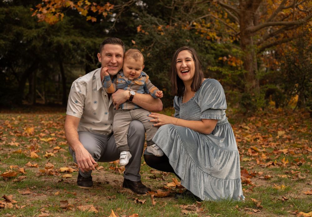 Family photo session outdoors with warm autumn colors and fallen leaves.
