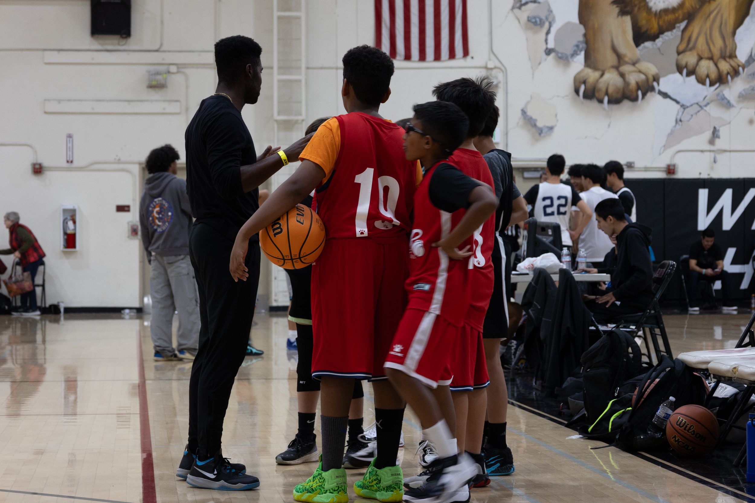Sports photograph of a team huddle around a coach who gives them direction of their game. The team is on the court while holding the ball