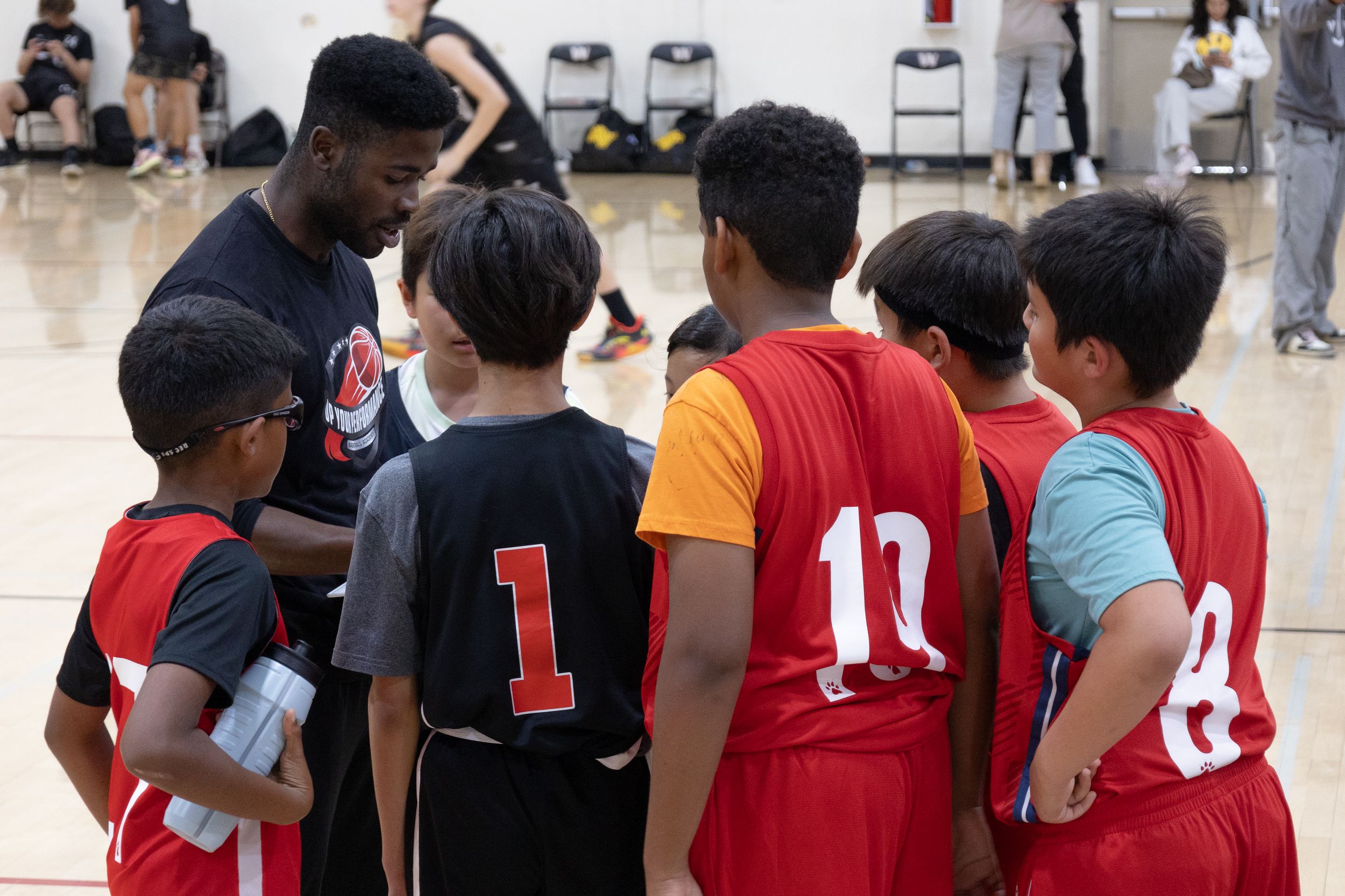 Youth team basketball team huddle listening to direction given from their coach. Up Your Performance club team. Team members lean in to hear