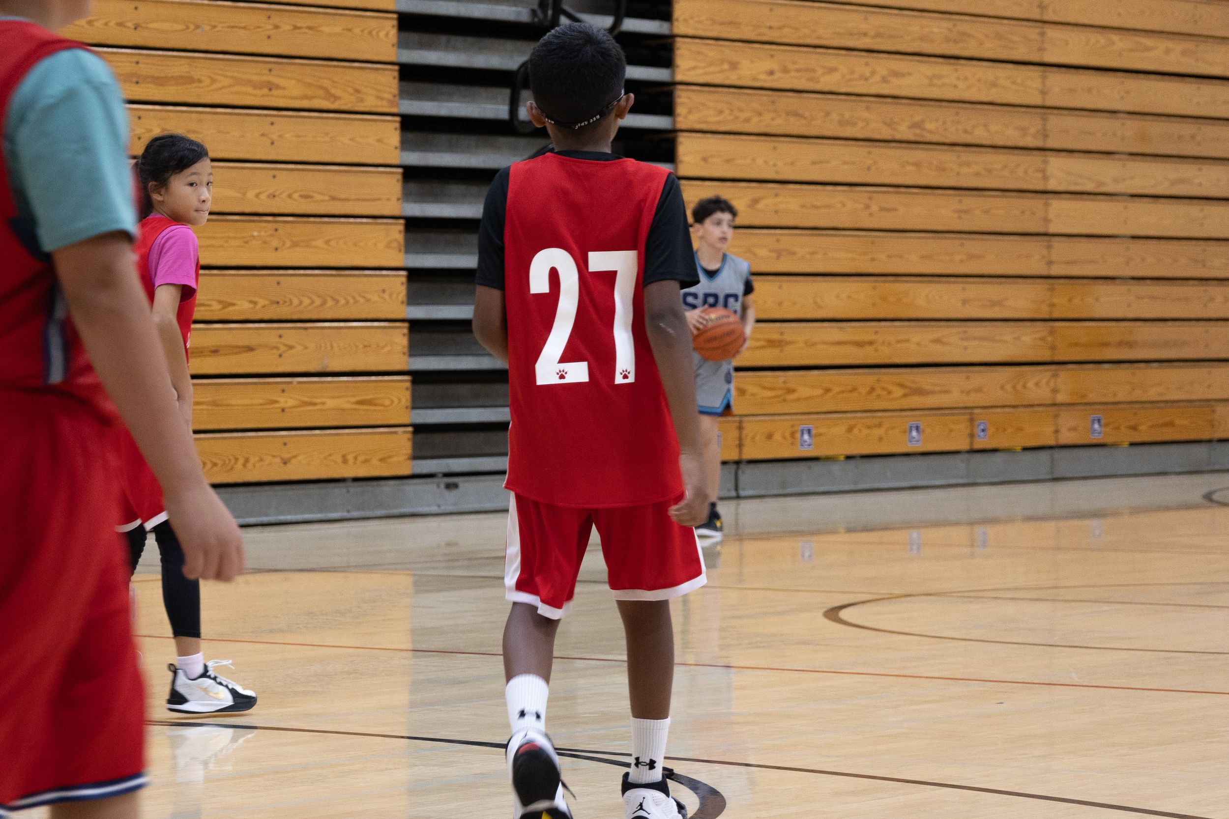 A basketball team stops and watches as the opposing team has the ball and lines up in a defensive formation to stop them from scoring.