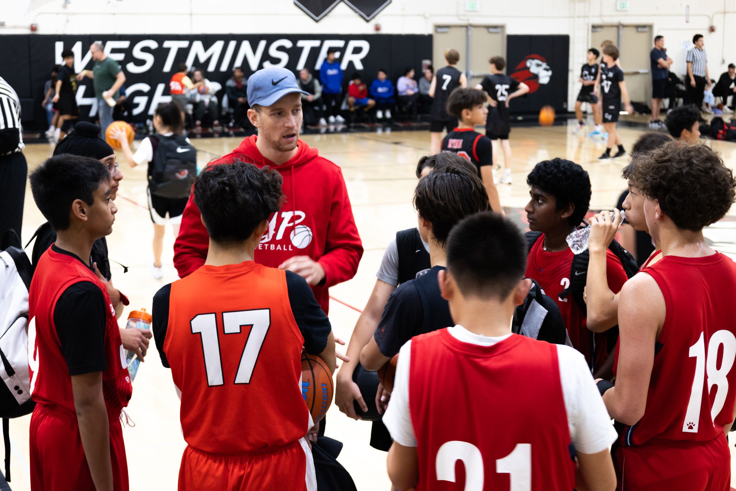 A basketball coach speaks to his players in candid photograph while team listens for next moves within the game.