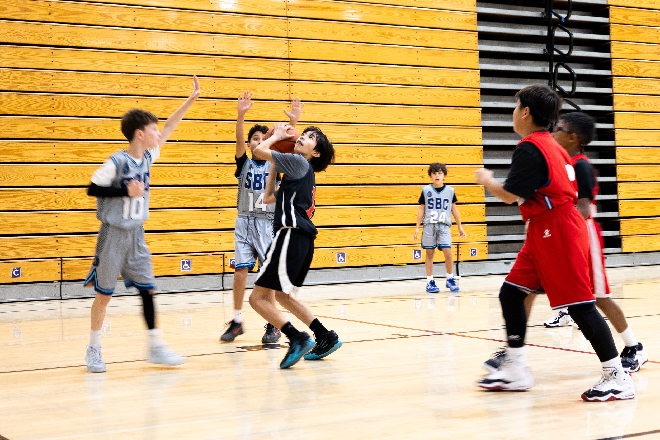 Basketball player shooting the ball while his teammate run to help and stop defenders. Candid sports photography.