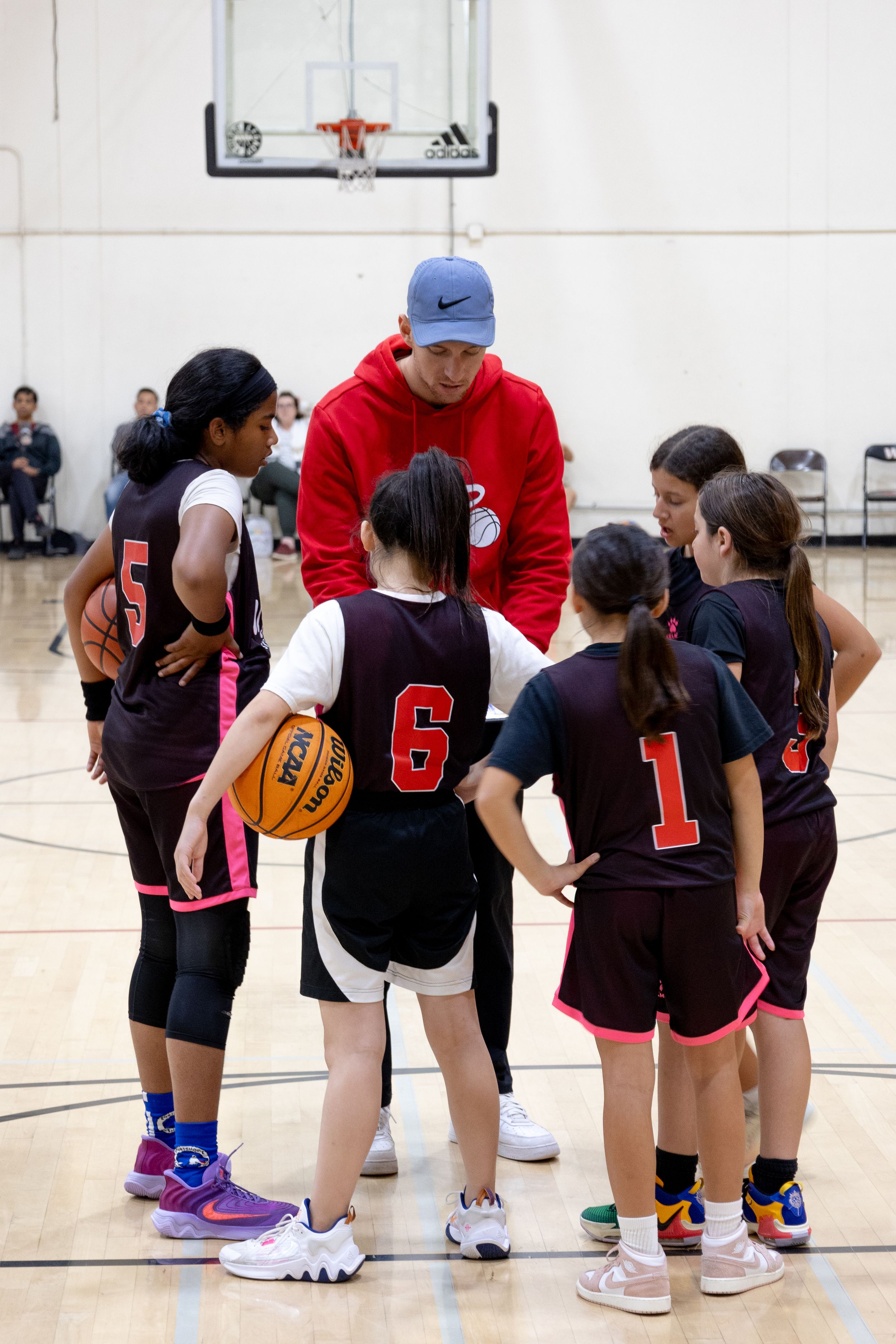 Youth Female basketball team huddle. Up Your Performance basketball club. Team huddled around coach displaying team work and playing a team.