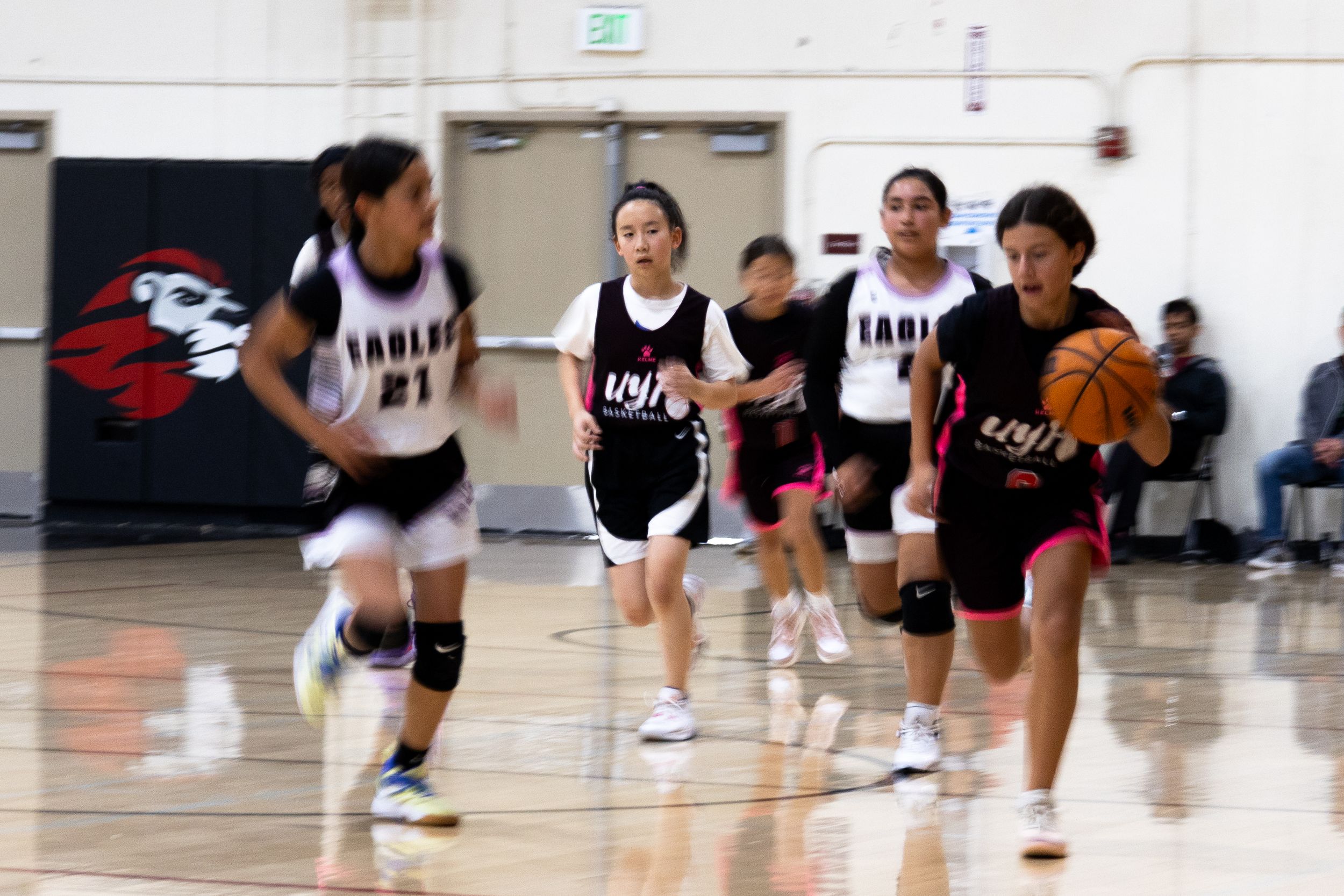 Candid action shot of a basketball player outrunning defenders while dribbling the ball down court. Youth basketball sport photography