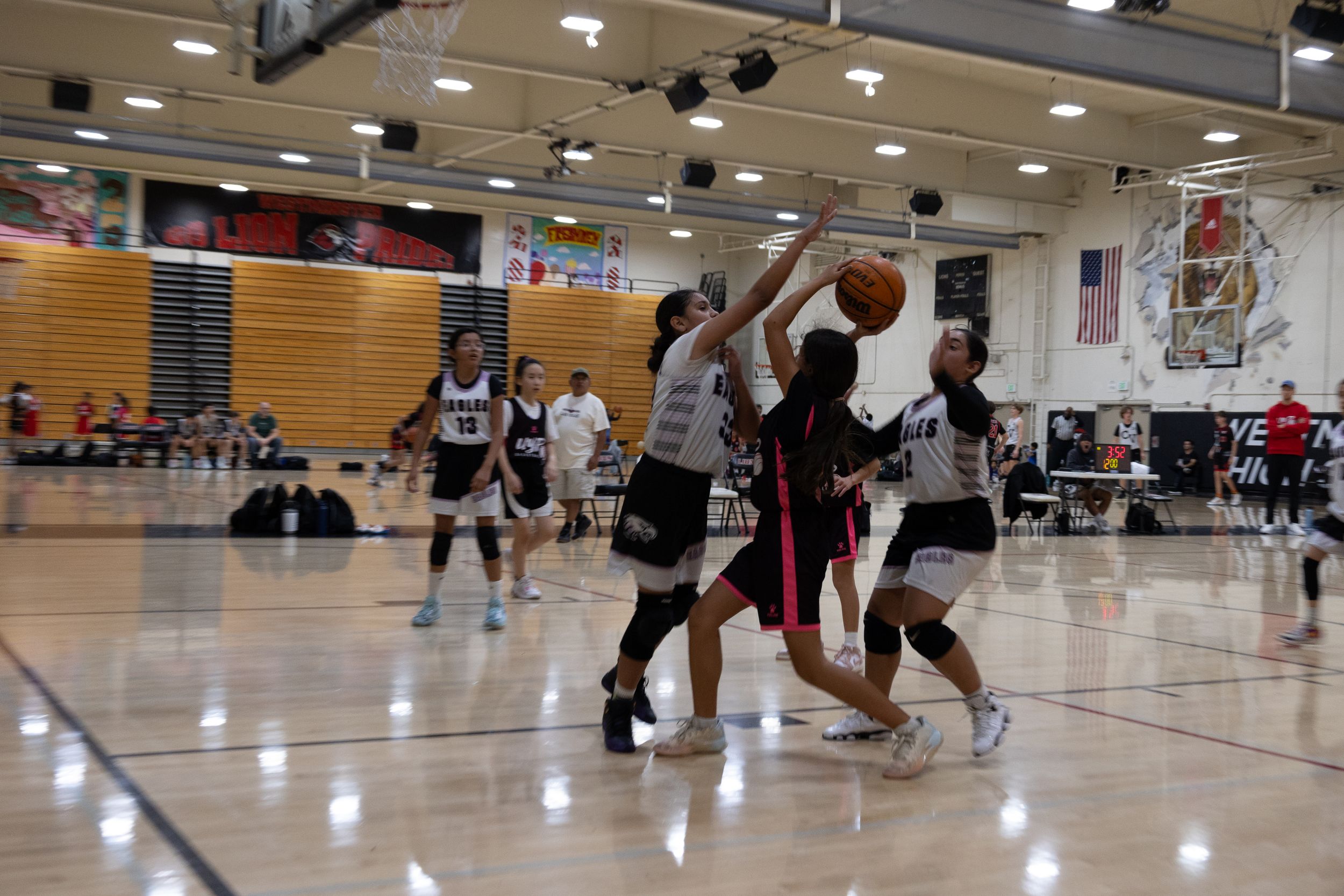 Candid, action sport photography of Basketball players in a mid-air scuffle while one team member tries to shoot the ball against blockers