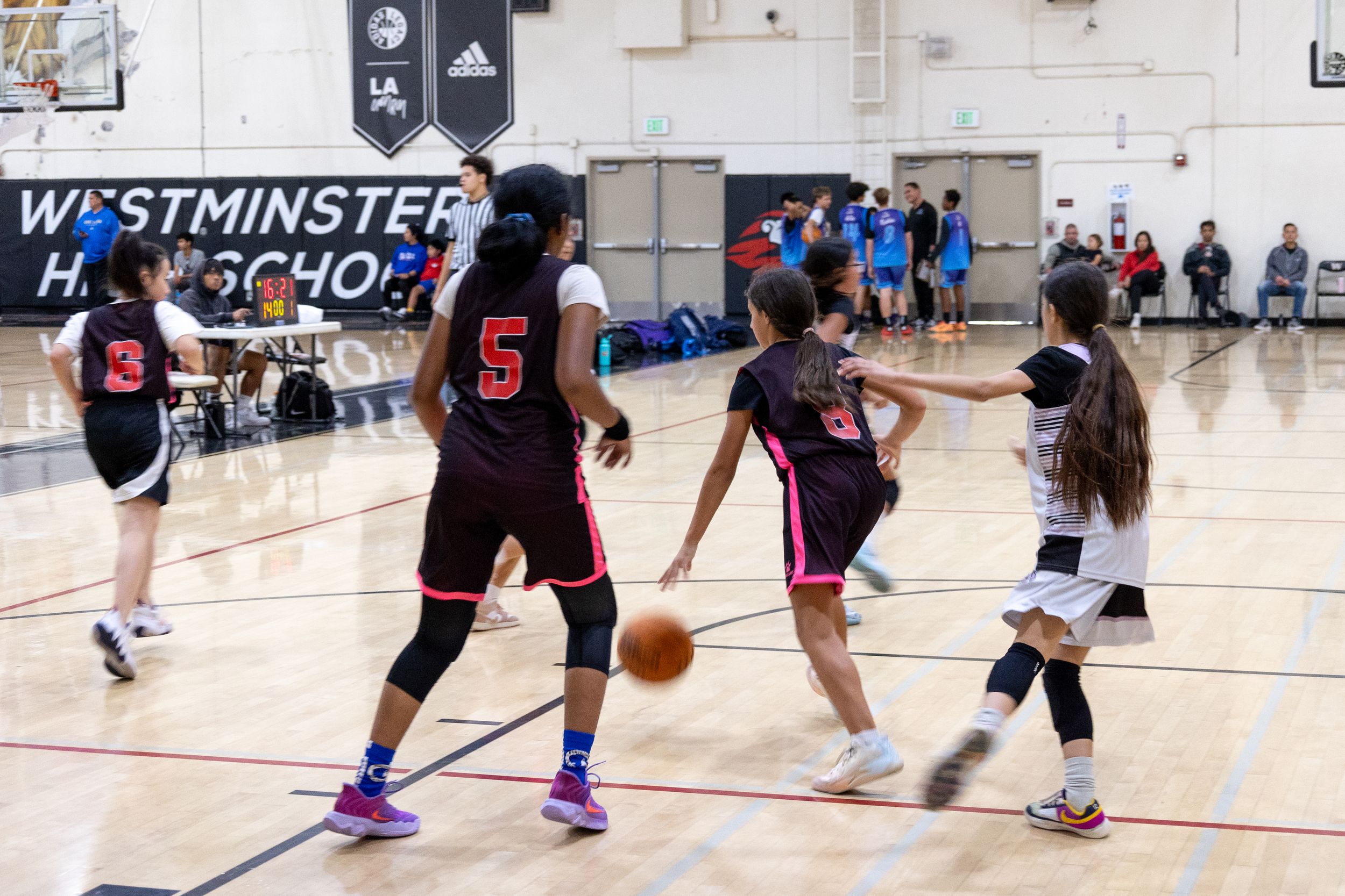 Candid photograph of a youth basketball team running dribbling a ball down a court and aligning to score a shot.
