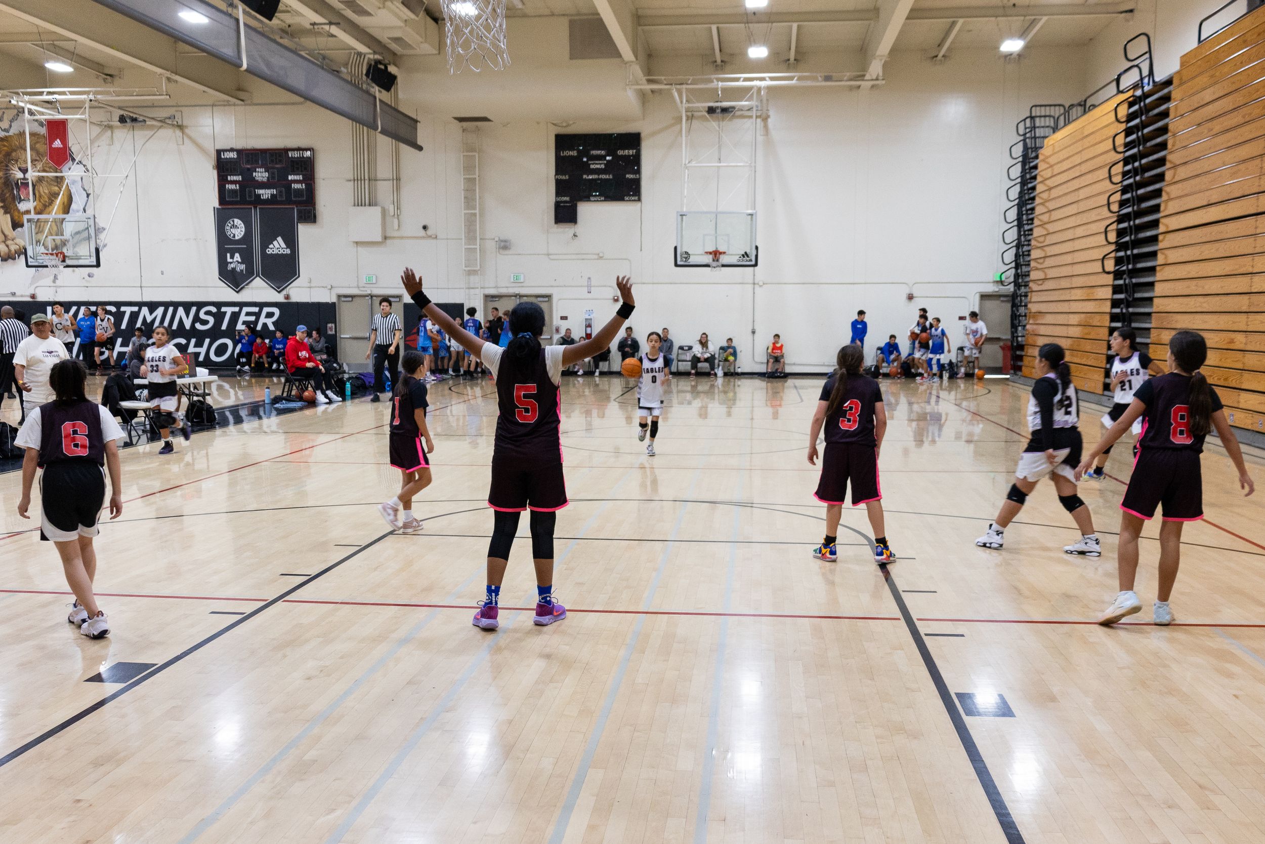 A youth basketball organizes themselves in a defensive stance at one side of the court waiting for opposing team. Candid sport photography