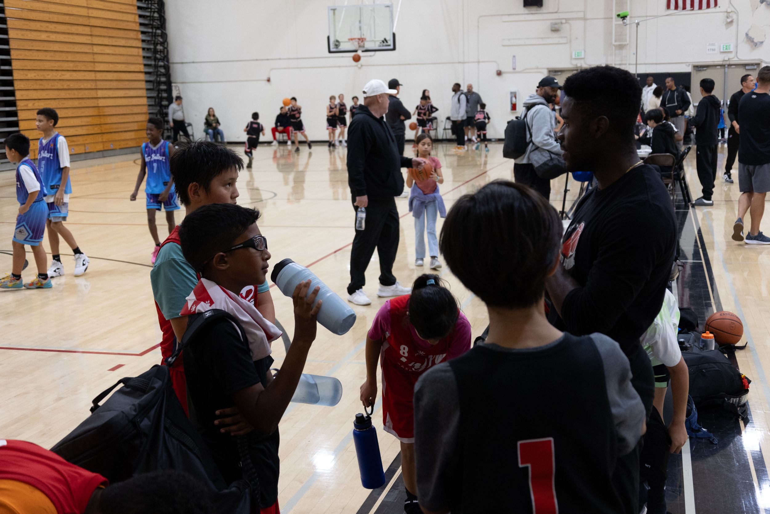 A candid shot taken of a coach congratulating his basketball team after winning a game. He provides game plans for their future practice