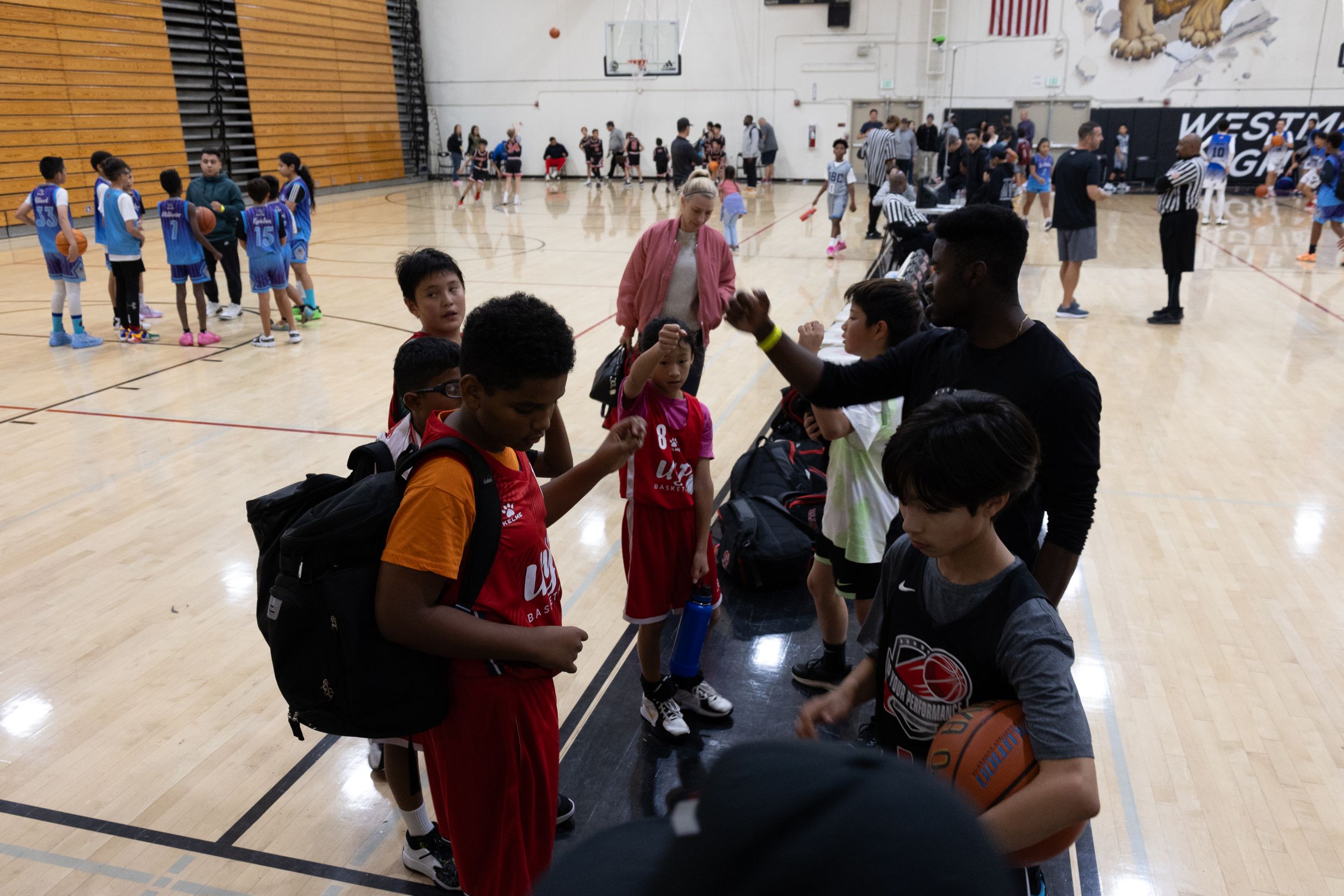 A candid shot taken of a coach congratulating his basketball team after winning a game. They are standing on a basketball court.