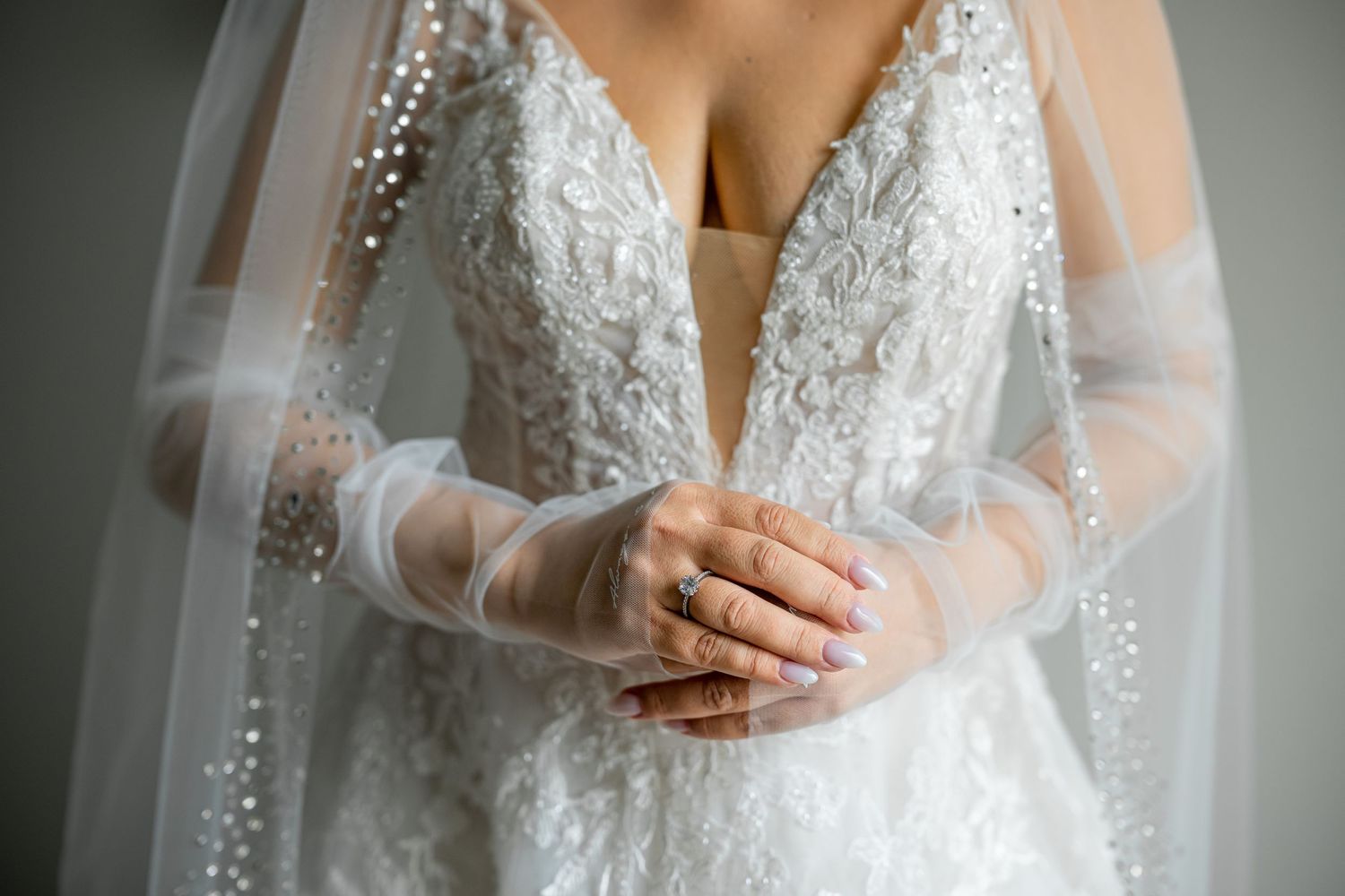 Detailed lace wedding dress with sheer sleeves and beaded embellishments.