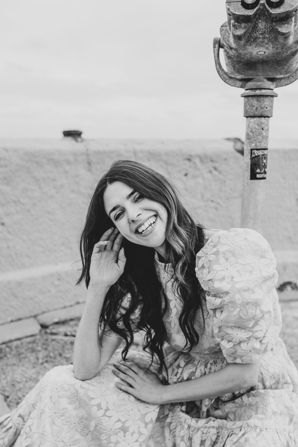 Black and white portrait showing joyful expression near vintage viewing station.