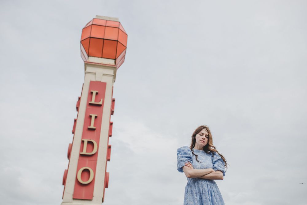 Blue dress outfit against iconic Lido sign tower on cloudy day.