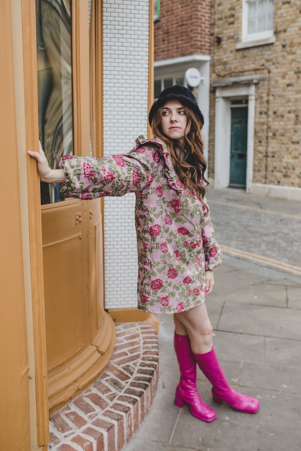 Floral dress and pink boots outfit near vintage doorway.