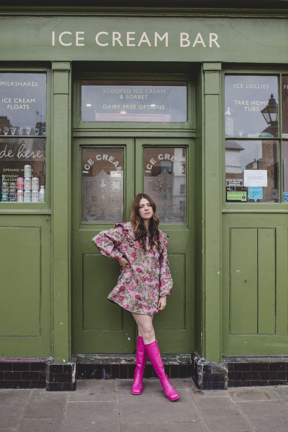 Pink boots and floral dress outfit in front of green ice cream shop.