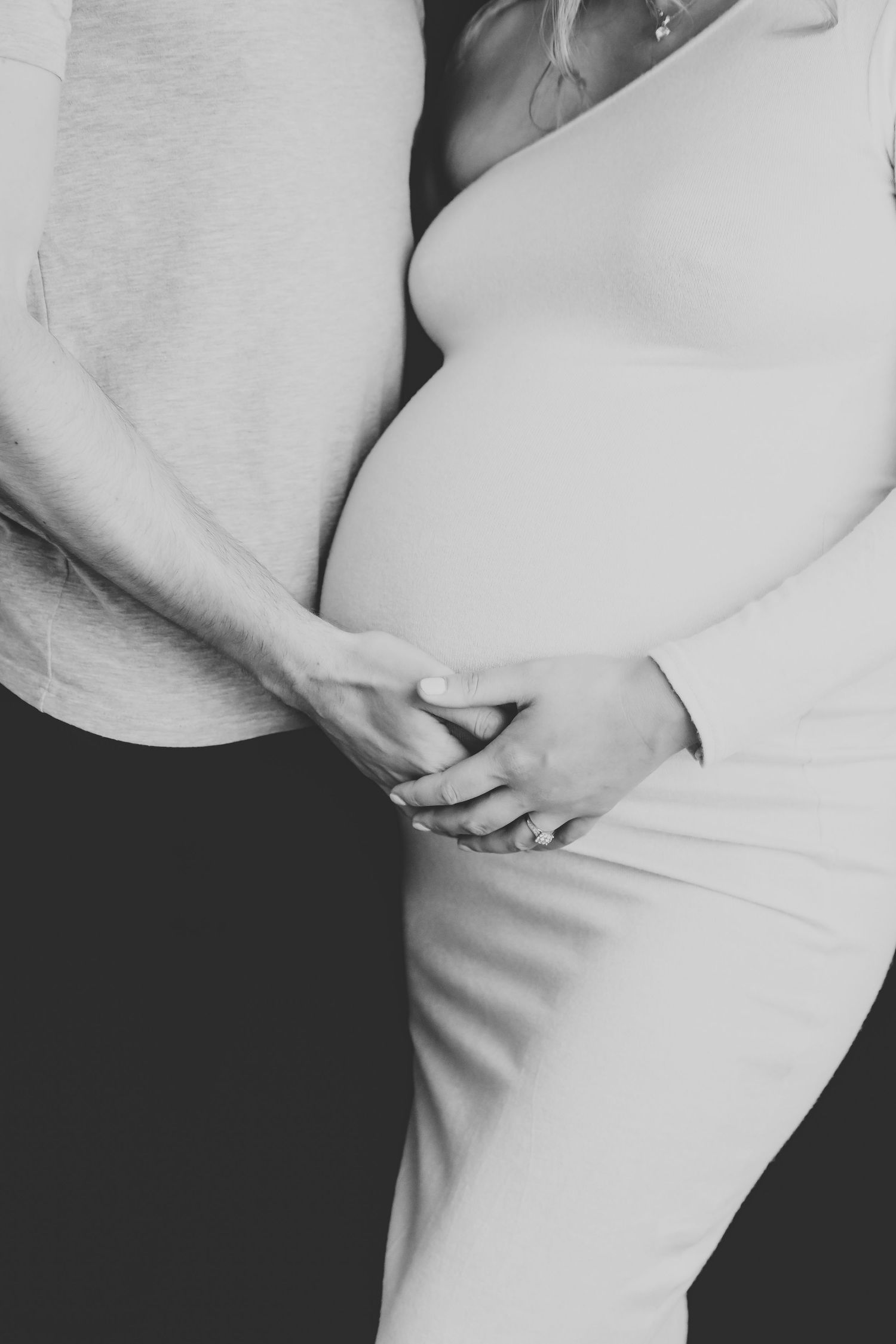 Close up view of a pregnant belly in casual clothing against a dark background. Photographer. Hull. East Yorkshire. Photography