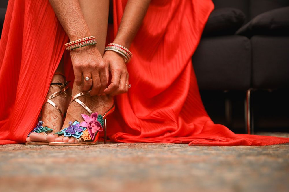 Detail shot of decorated feet and red sari hem against carpet during Indian wedding. Hindu Wedding Photography